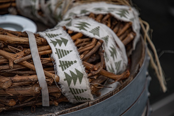 Tightly wound sticks in the shape of a Christmas wreath with Christmas ribbon wrapped around it