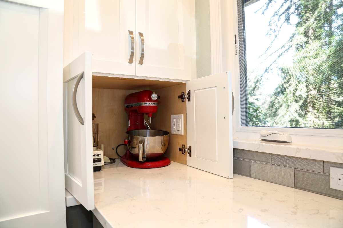 Small white cabinet appliance garage with a red stand mixer in it