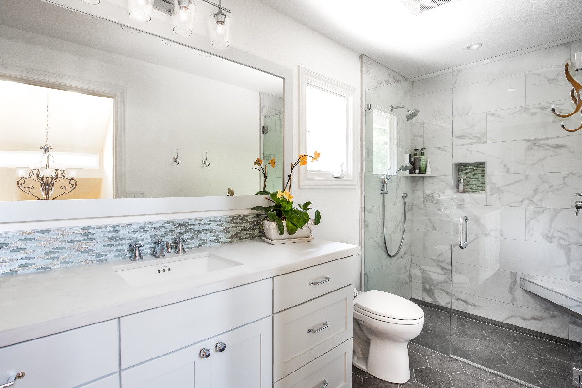 Curb-less shower with a wide countertop space with wall length mirror and single bathroom sink and basin