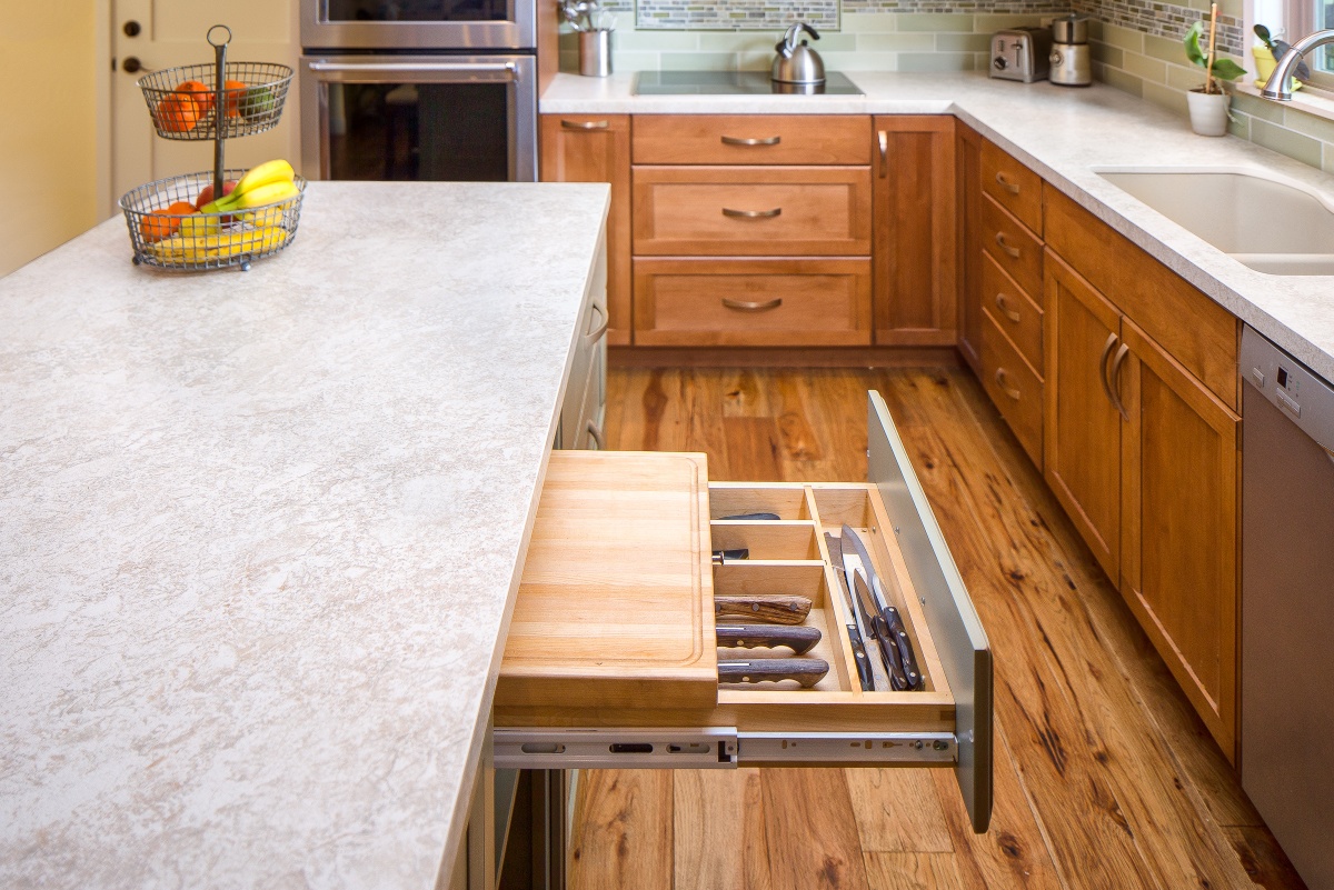 Kitchen drawer with diningware and silver ware and a built in cutting board that slides out