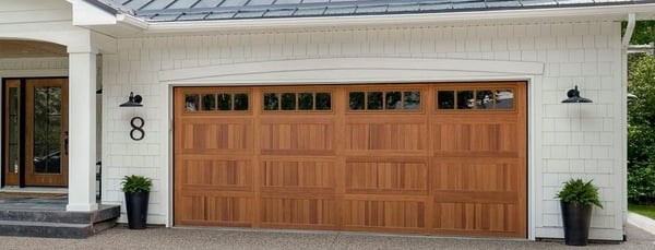Contemporary wooden garage door with window paneling and a large front door