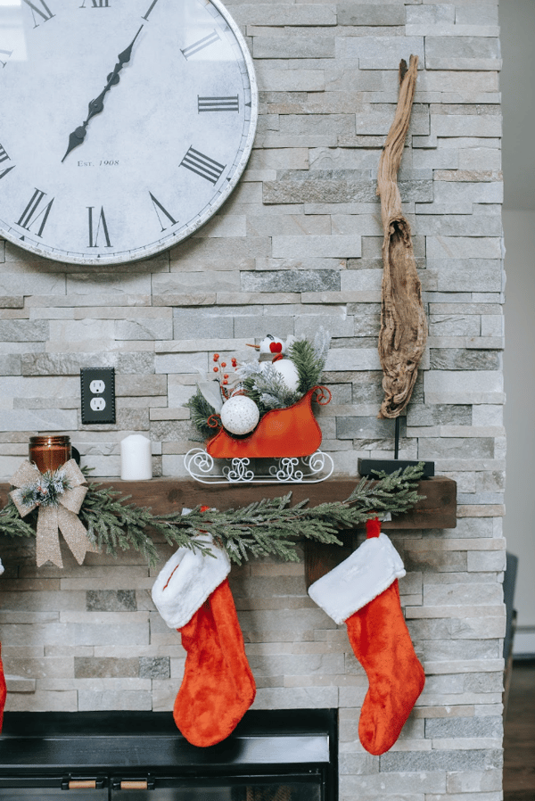 Christmas holiday centerpiece over the fireplace directly above the red stockings that are hung