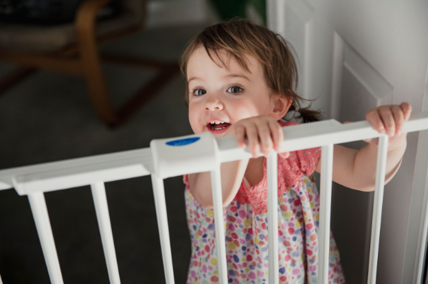 Young girl peering over a child gate to look at remodeling contractors in the home