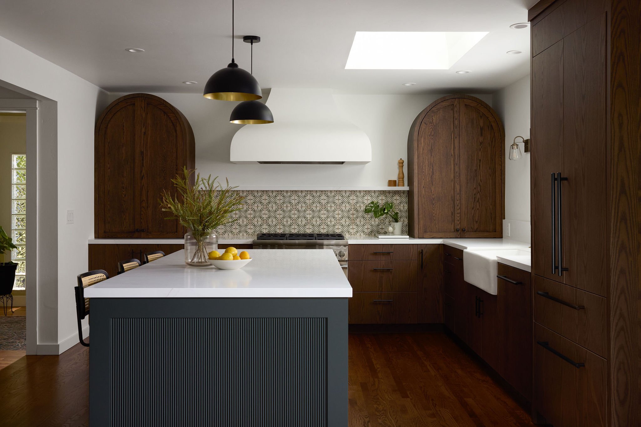 Simple, yet elegant kitchen remodel with dim natural lighting for a cozy and inviting feel. A bowl of lemons and plan arrangement sit on the island.
