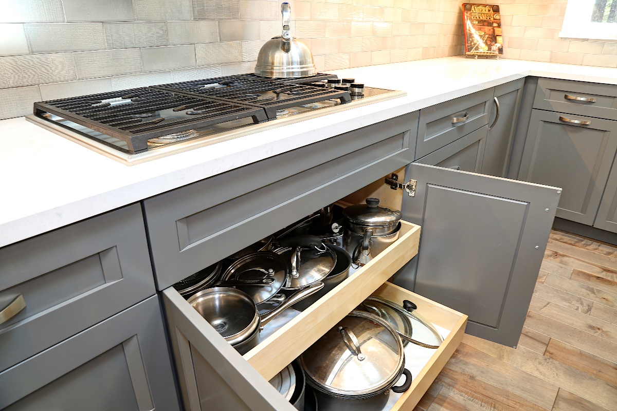 Grey cabinets featuring a cooktop pullout cabinet set for pots and pans and lids