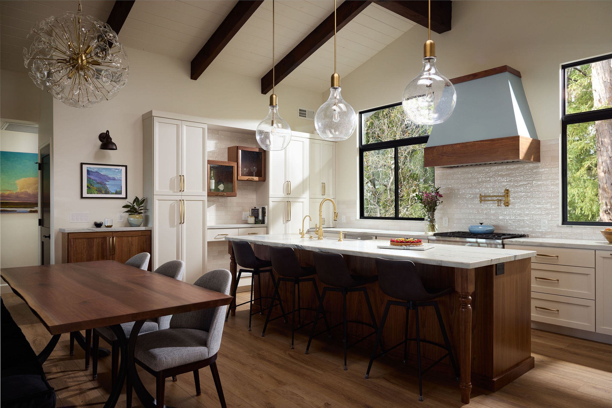 West Coast kitchen remodel with white cabinetry, gold trim, and a kitchen island with bar stool seating and a prep-station