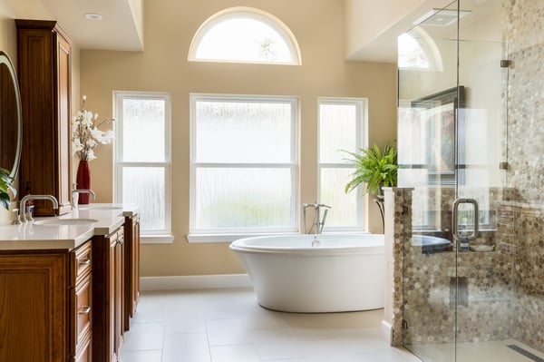 Luxury remodeled bathroom with standalone tub, stone backsplashes and rich wooden cabinetry