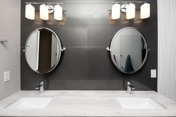 Dark modern bathroom with double vanity, 2 mirrors, and soft white lighting