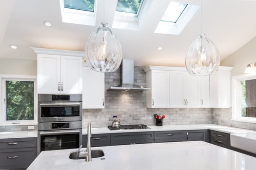 suspended lighting fixtures with glass shades hanging over a kitchen island