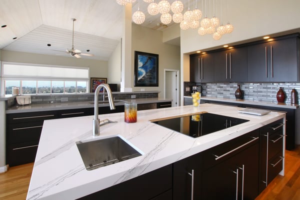 Luxury kitchen remodel with an island that has a glass backsplash in the background