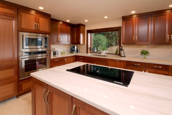 Rustic kitchen remodel with warm wooden cabinets, natural light and a backsplash with the same material as the countertop