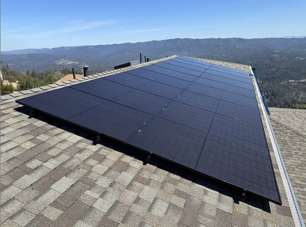 Residential solar panels mounted on a rooftop overlooking a mountainside