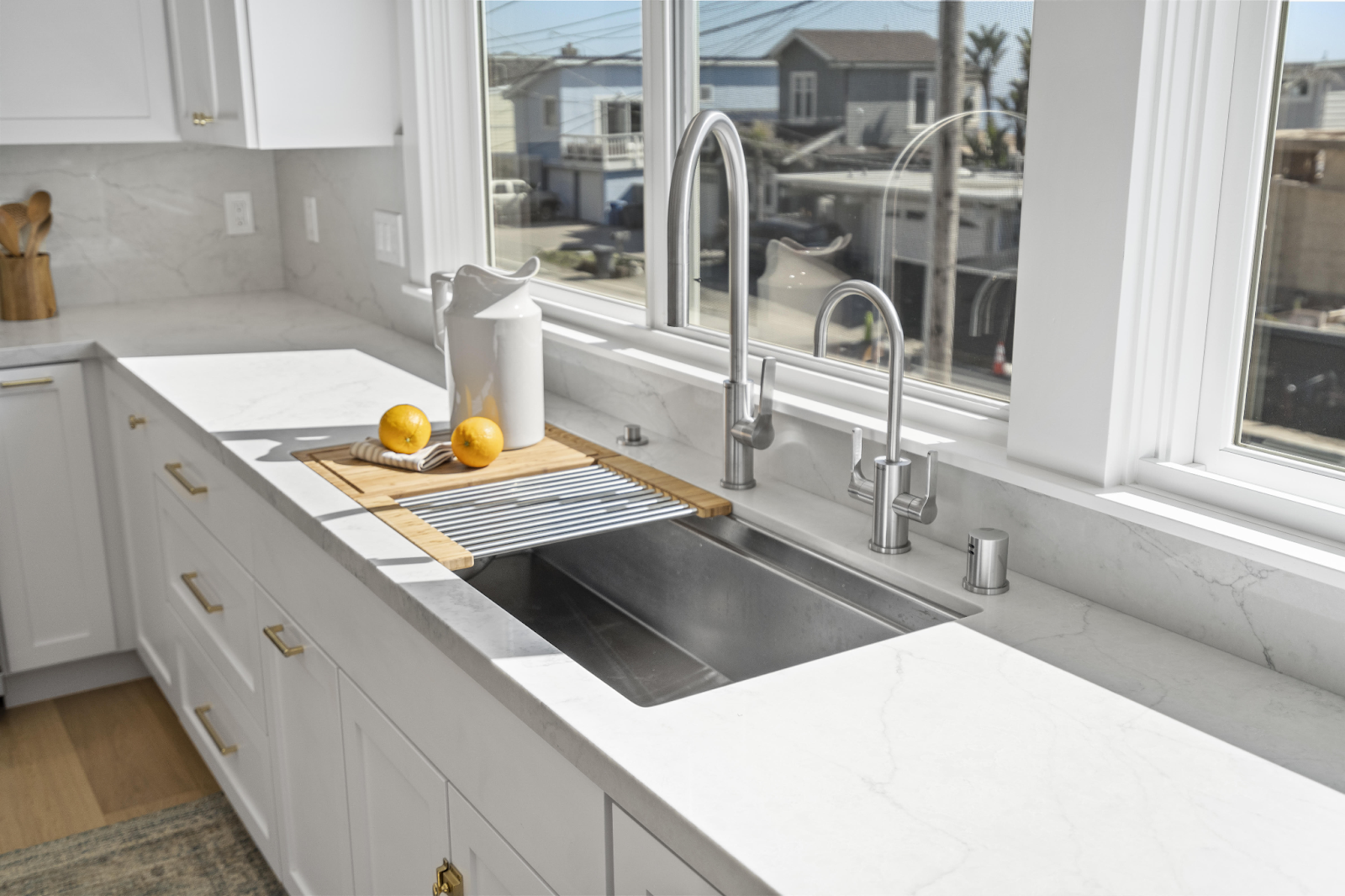 A kitchen sink with two faucets, a double-wide basin, and a mixture of gold and silver metal finishes
