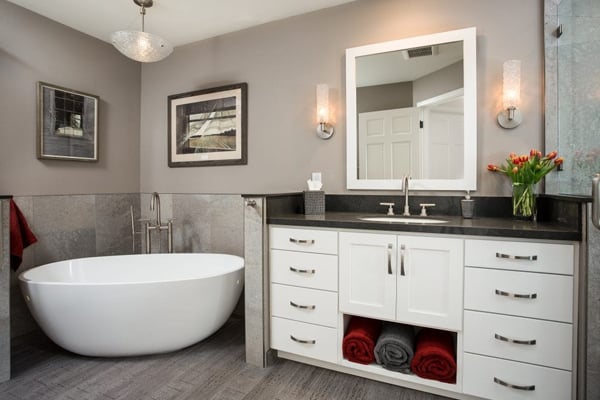 Bathroom with white cabinet, grey walls, and a stand-alone tub