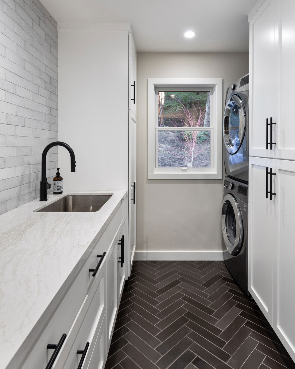 Beautiful laundry room with white cabinets and grey chevron floor tiles