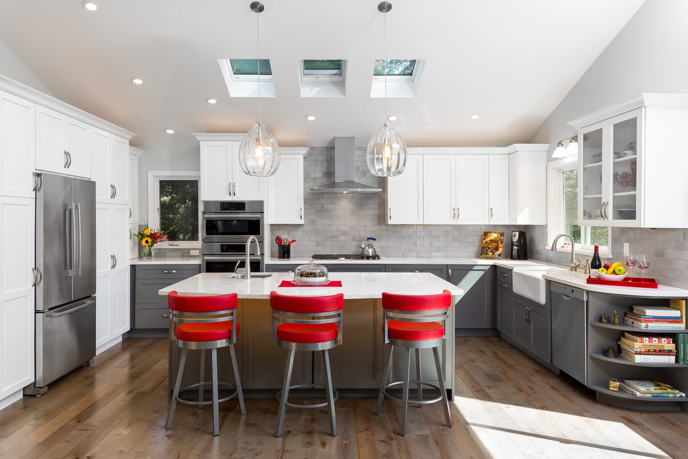 After kitchen remodel with three skylights, red barstools, and white cabinetry