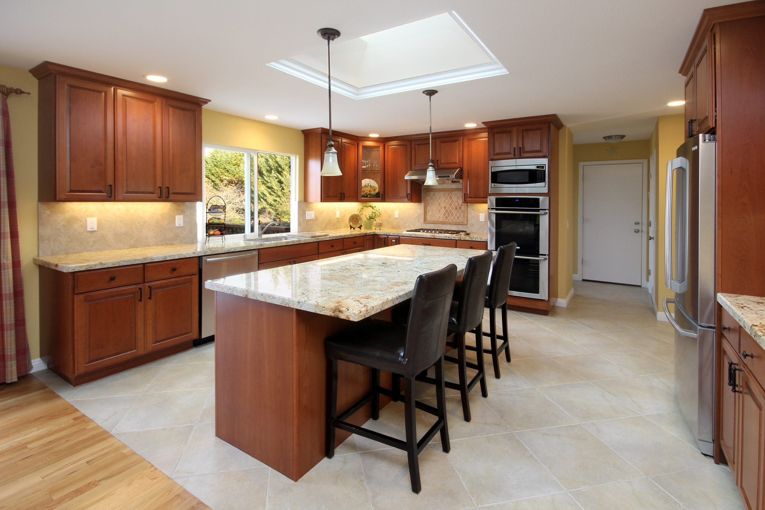 Kitchen remodel after photo showcasing finished cabinets, a stand-alone island, and a skylight