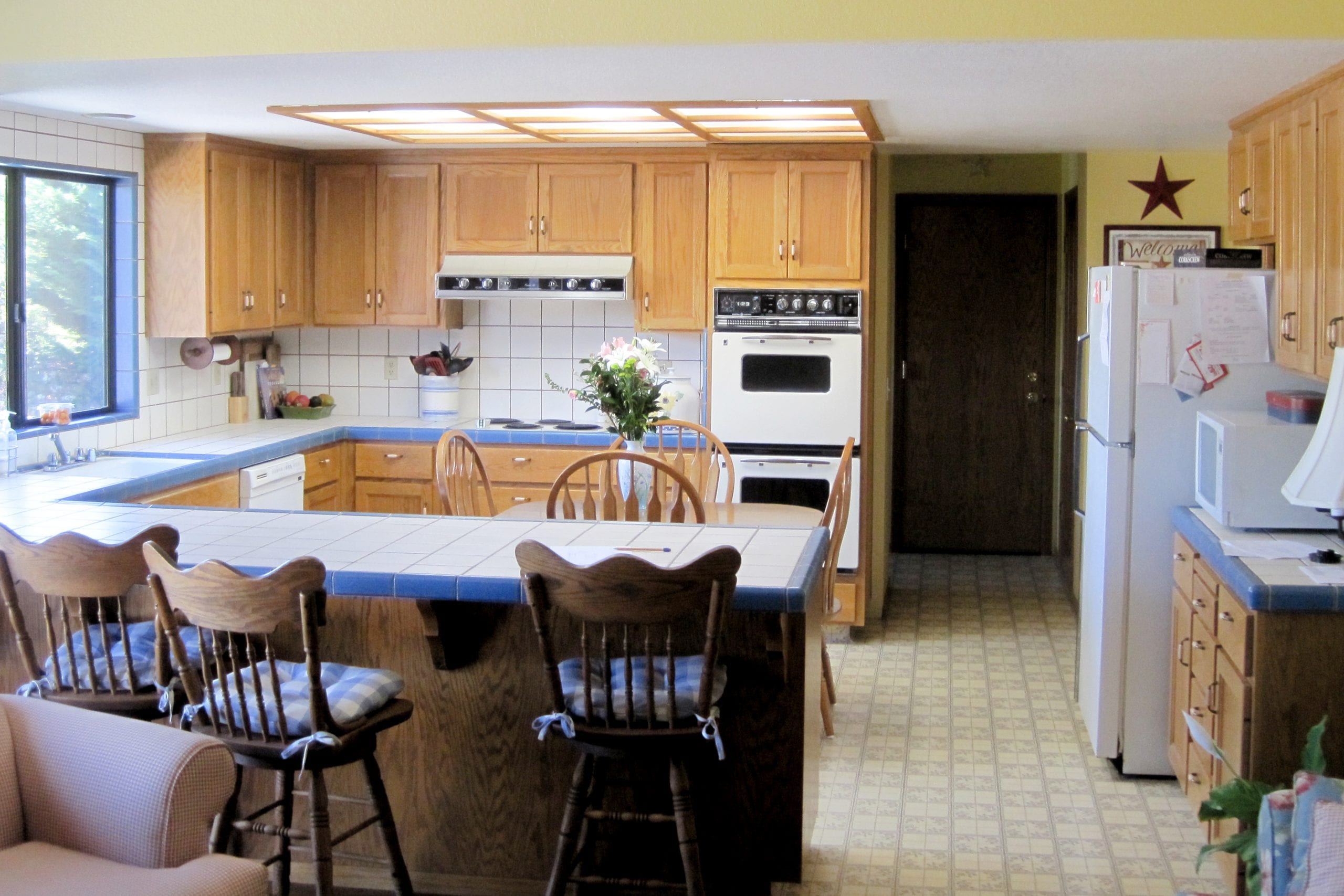 Kitchen remodel before photo showing tile countertops and wooden furnishing
