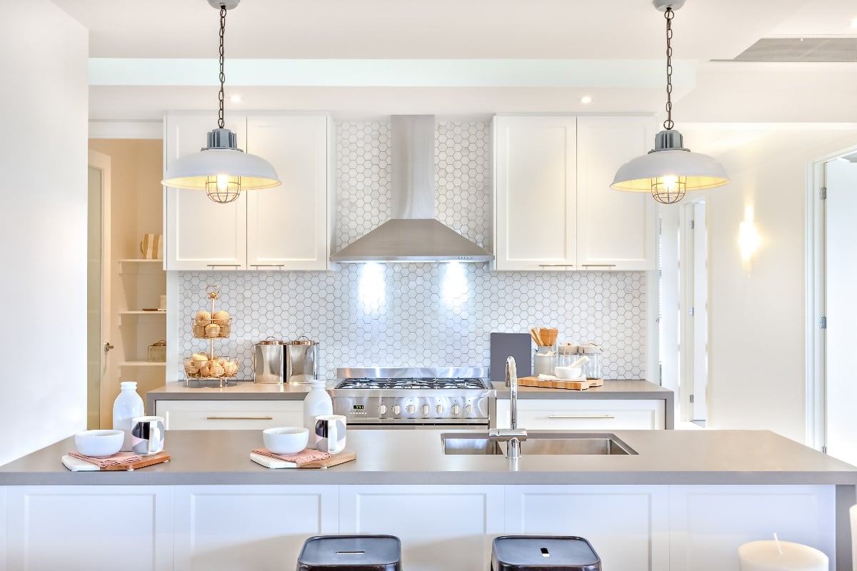 Bright and inviting kitchen remodel with white cabinets, overhead lighting, stainless steel appliances, and an island with bar style seating