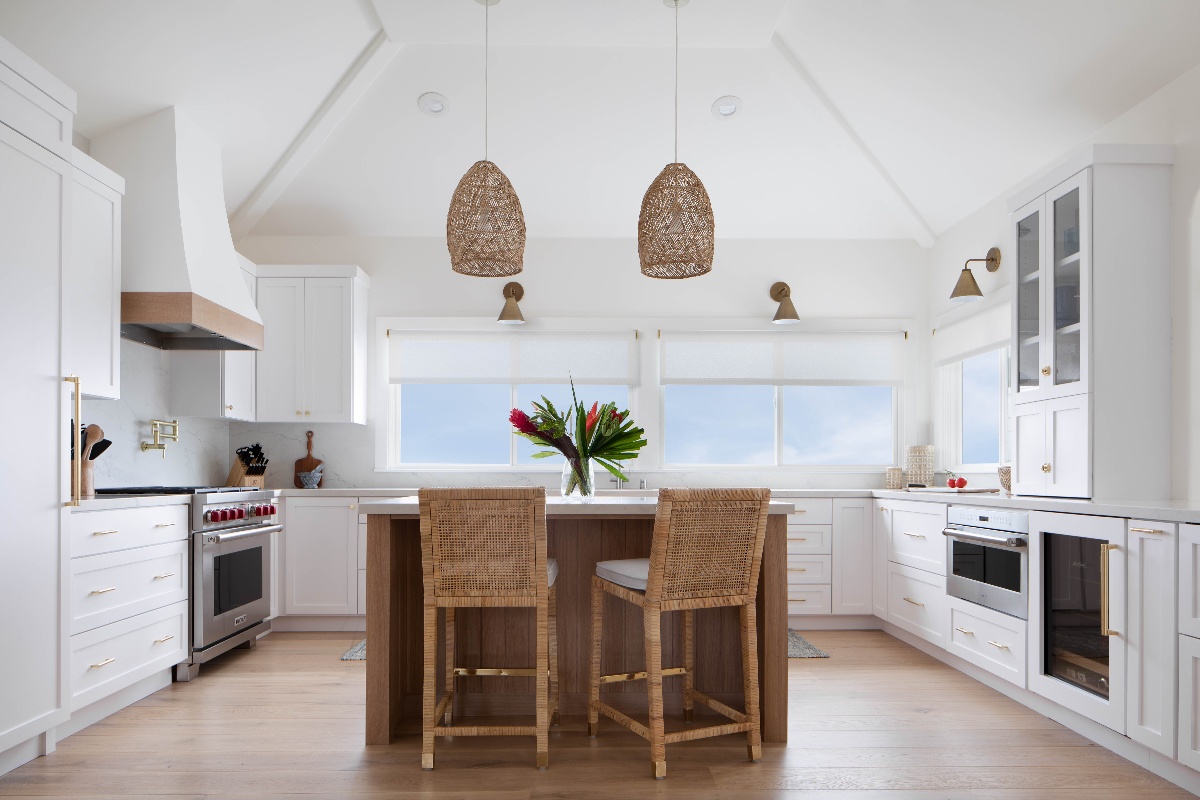 Wide angle view of a kitchen island with 2 wicker bar stool chairs and two suspended wicker lights