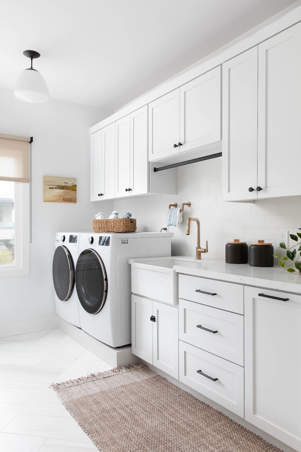 Laundry room and mud room with white tile flooring and lots of white storage cabinets