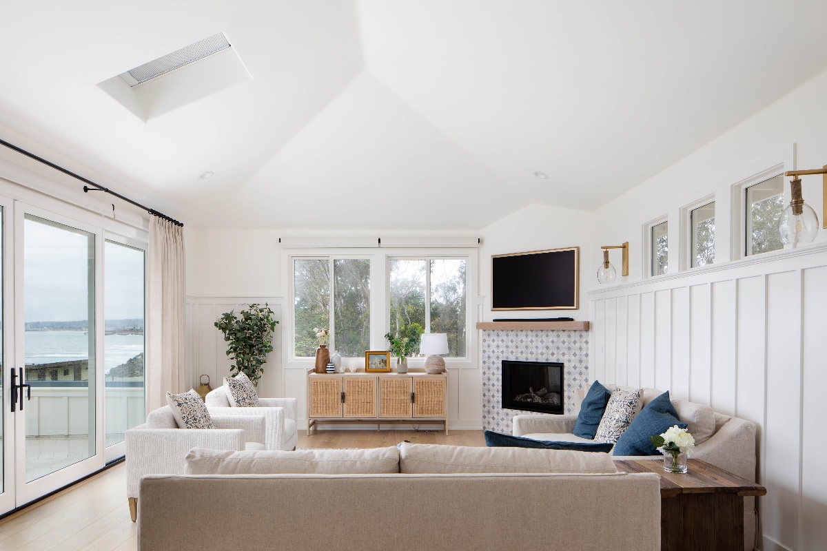 All white living room remodel with sandy brown couch, light wood accents, and large sliding glass doors