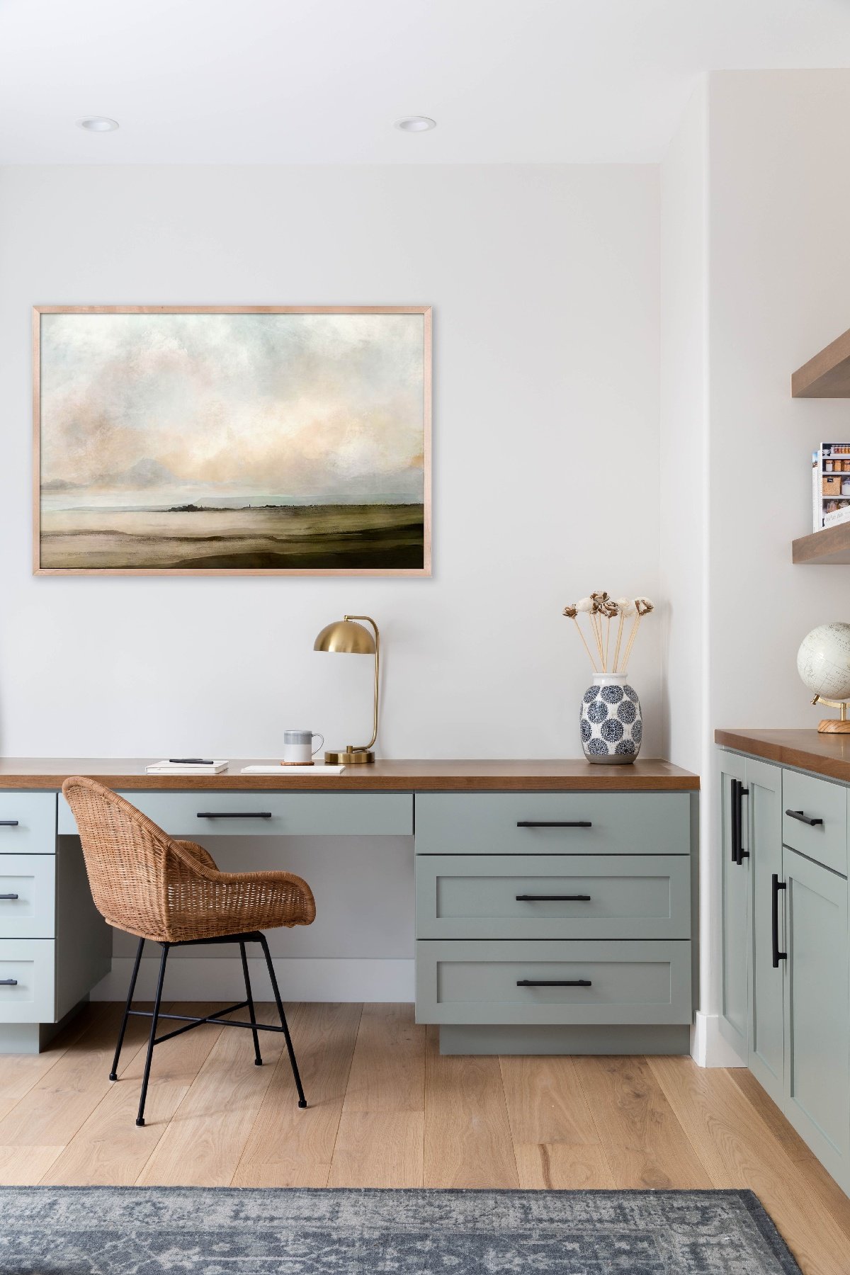 Home study with a wicker chair and a pastel mural painting hung above the desk