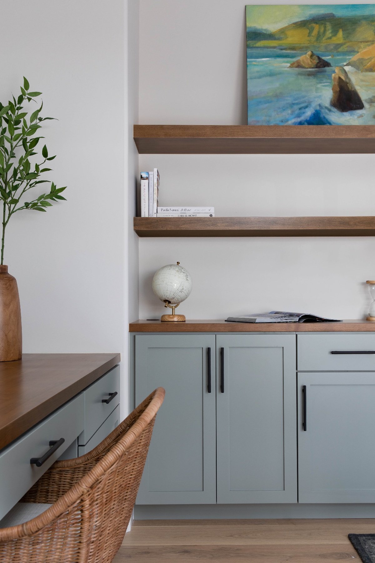 Close up of pastel and pale blue storage cabinets with wooden floating shelves wall mounted above.