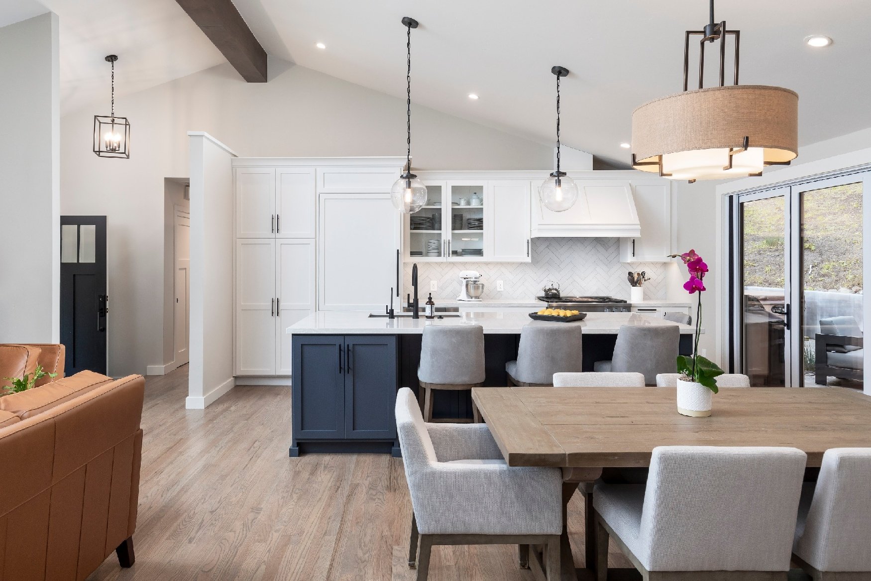 Inviting kitchen and dining area with tan hanging lights and black countertops