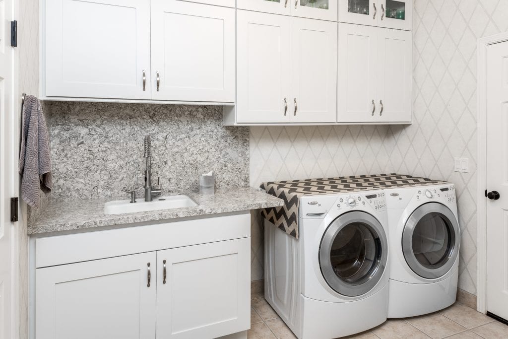 Elegant laundry room with white cabinets, a built in sink, and washer & dryer combo