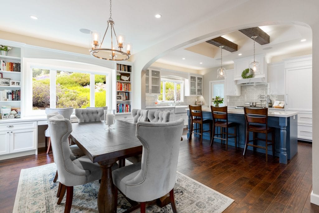 Kitchen and dining room with dark wood furnishings, white cabinetry, and lots of natural light