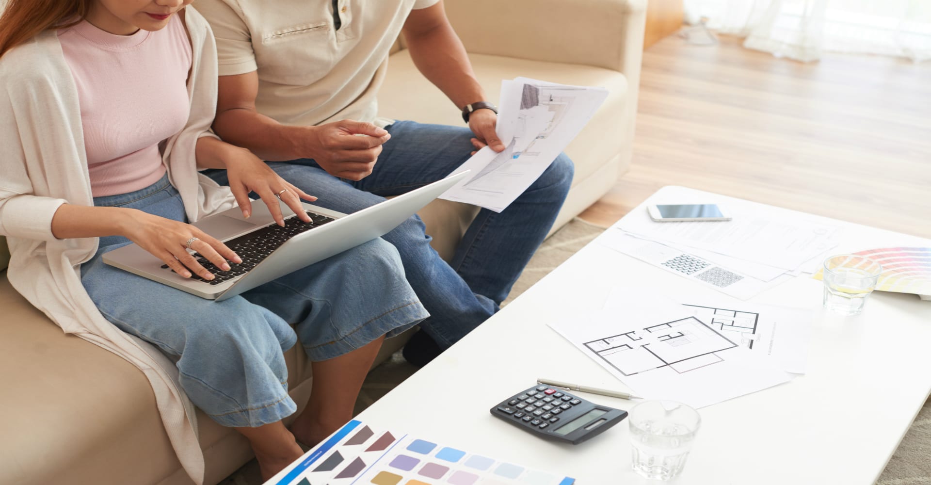 Two people reviewing a floor plan together. Hard wood floor in the background.