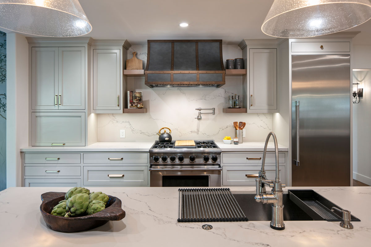 Open space kitchen with white marble countertops and matching white cabinetry