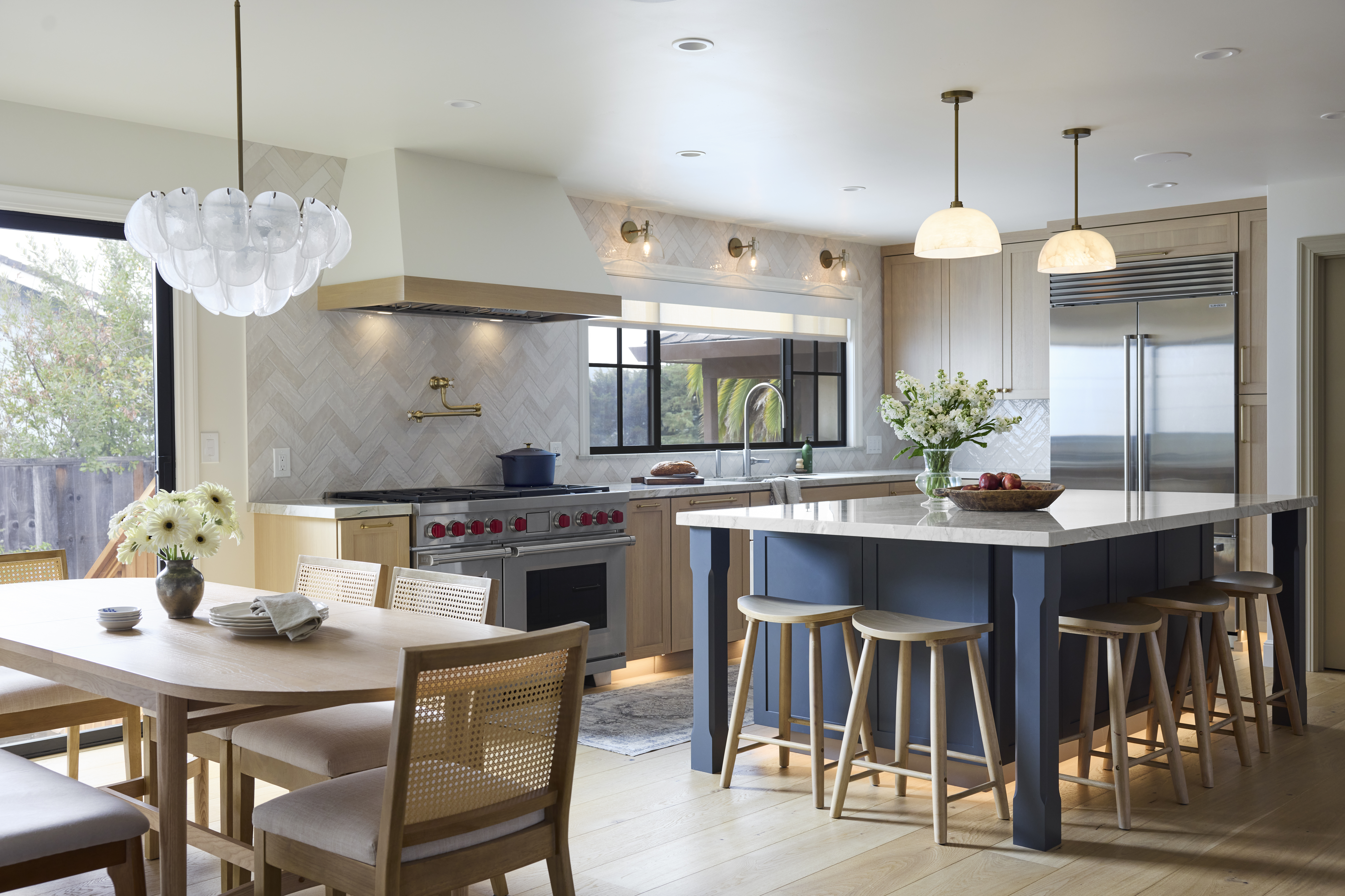 Kitchen remodel with white oak and painted cabinets, stainless steel appliances, and five barstools