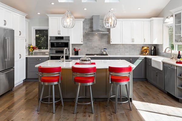 Kitchen remodel with white cabinets, stainless steel appliances, and red barstools