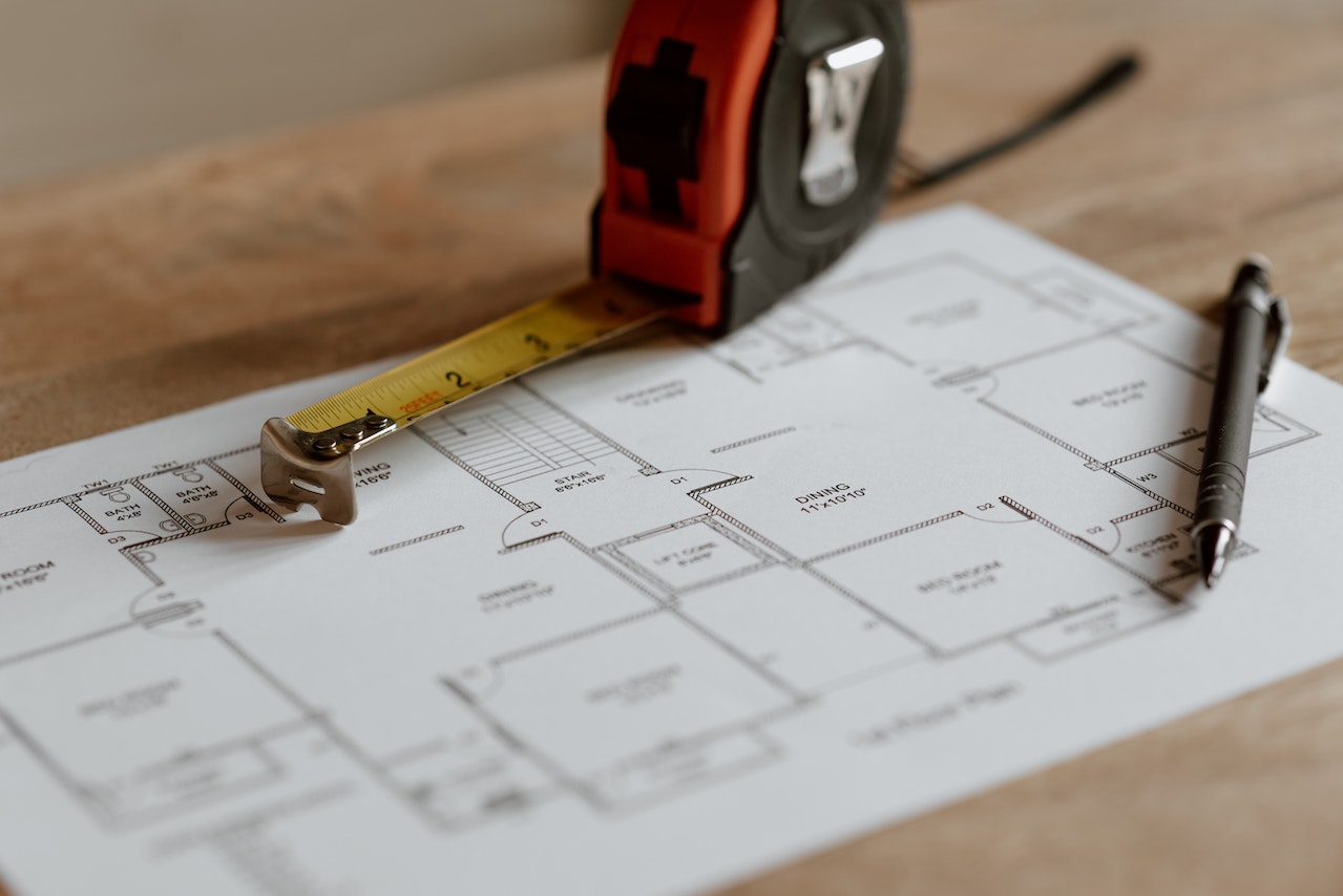 Architectural plan of a home remodel with a measuring tape and pencil