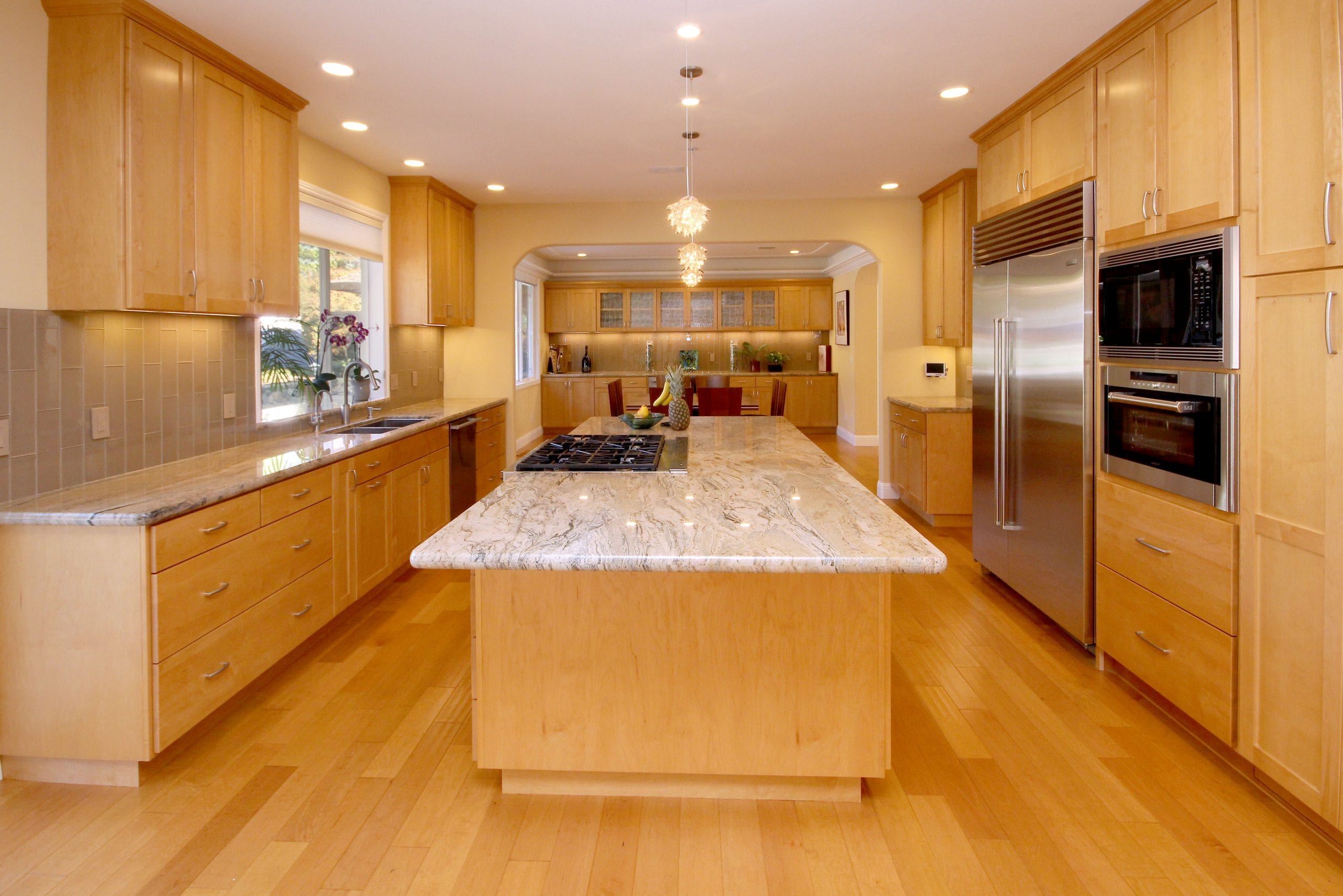 Kitchen remodel after with light wood finishing and granite countertop