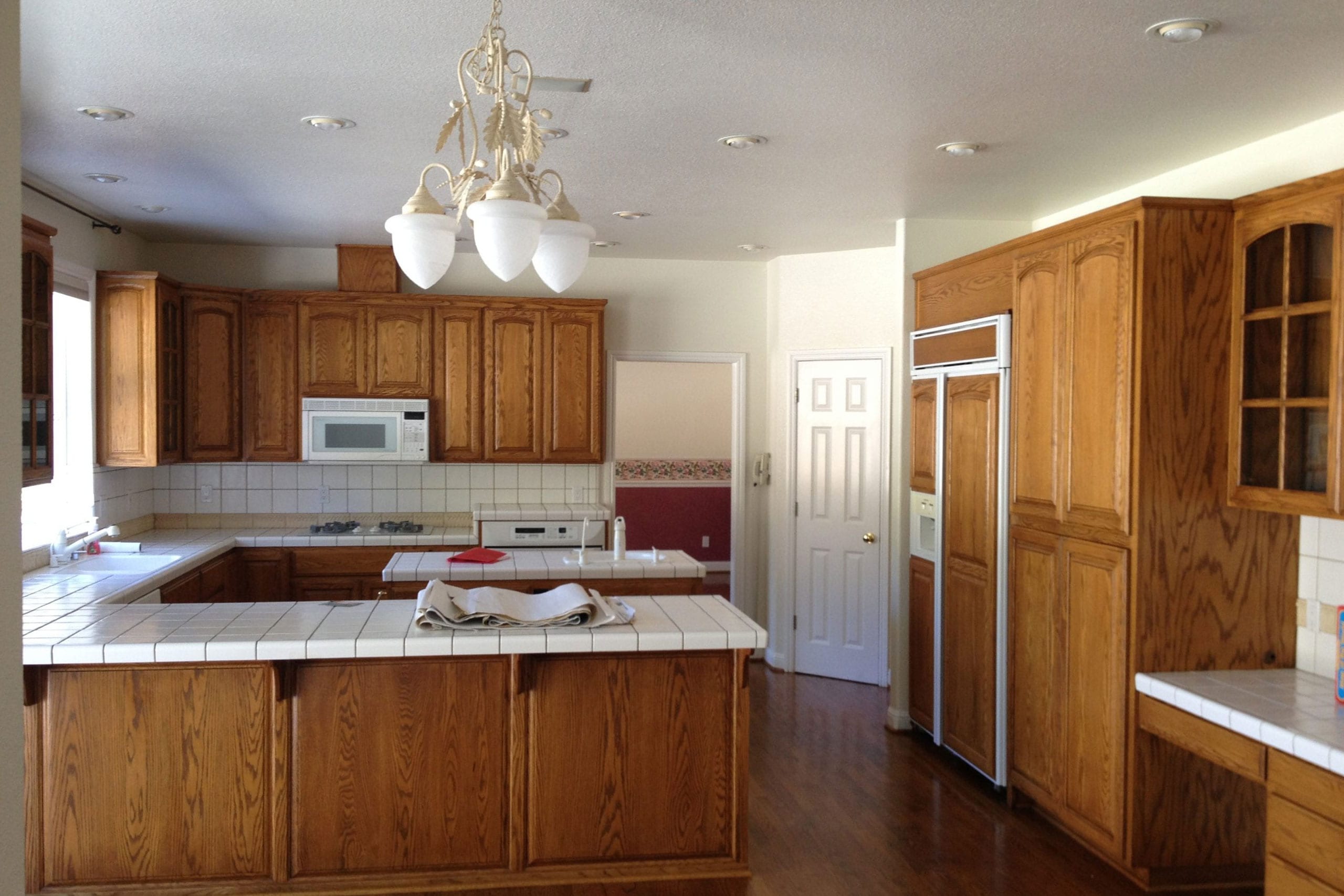 Kitchen remodel before with dim lighting and tile countertops