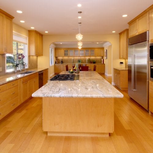 Stand alone kitchen island with hanging ceiling lights and built-in stove top