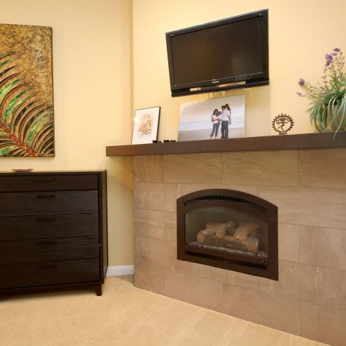 Stone fireplace with TV mounted above wooden mantle