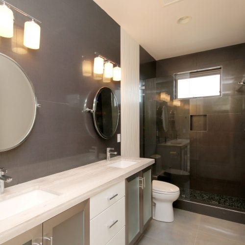 Black and white bathroom with round mirrors and a black tile walk-in shower