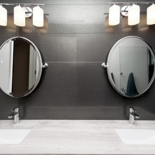 Bathroom with black tile back splash and double round mirror vanity