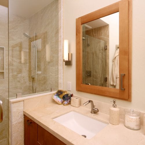 Bathroom sink next to a walk-in shower with a sliding glass door