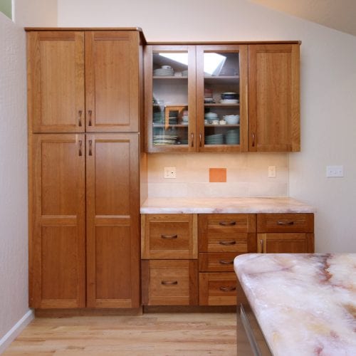 Wall of wooden cabinets with tiled backsplash cut-out