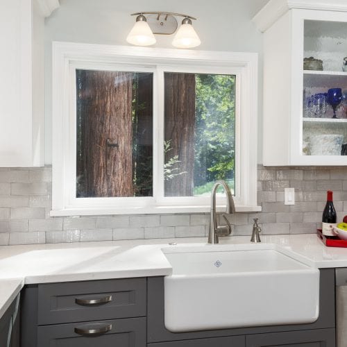 White countertop and kitchen sink in front of a sliding window