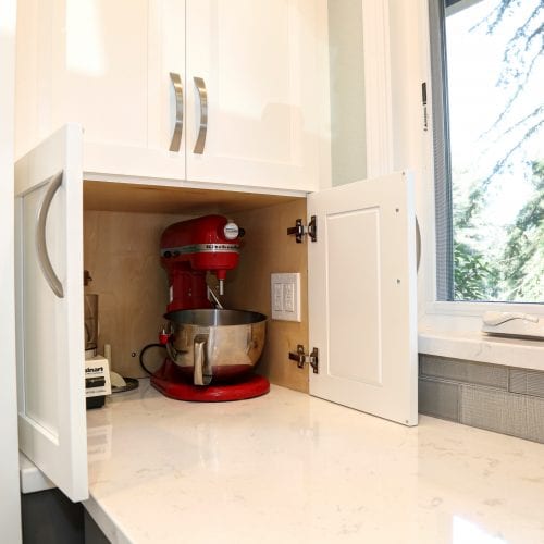 Kitchen cabinet with red stand mixer stored inside