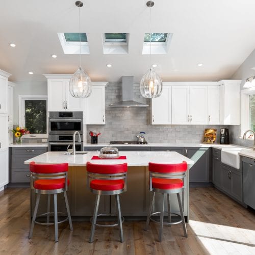 Elegant kitchen remodel with red barstools, skylights and ceiling lights