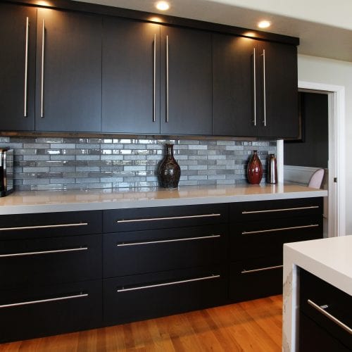 Black cabinets mounted to the wall with dark grey backsplash 