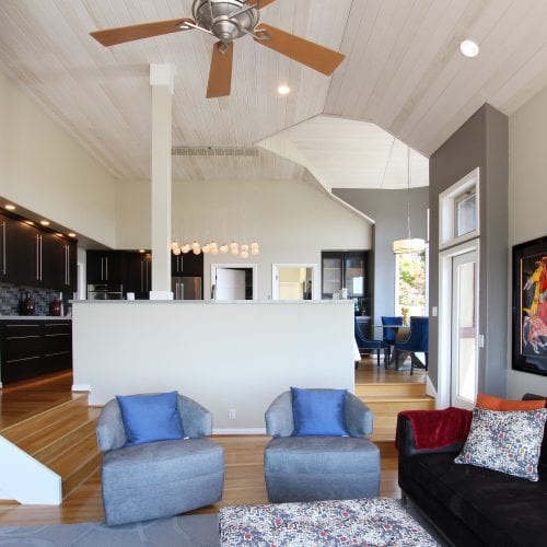 Living room chairs with blue pillows sit in front of kitchen