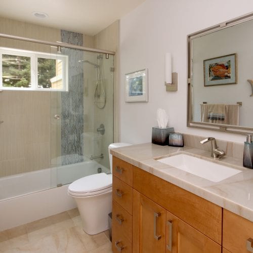 Bathroom remodel with wooden cabinet, marbled countertop, and a sliding glass shower door